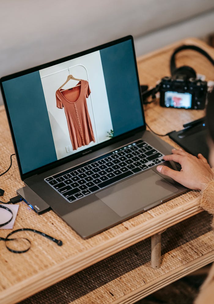 Professional photographer editing clothing images on a laptop with camera nearby.