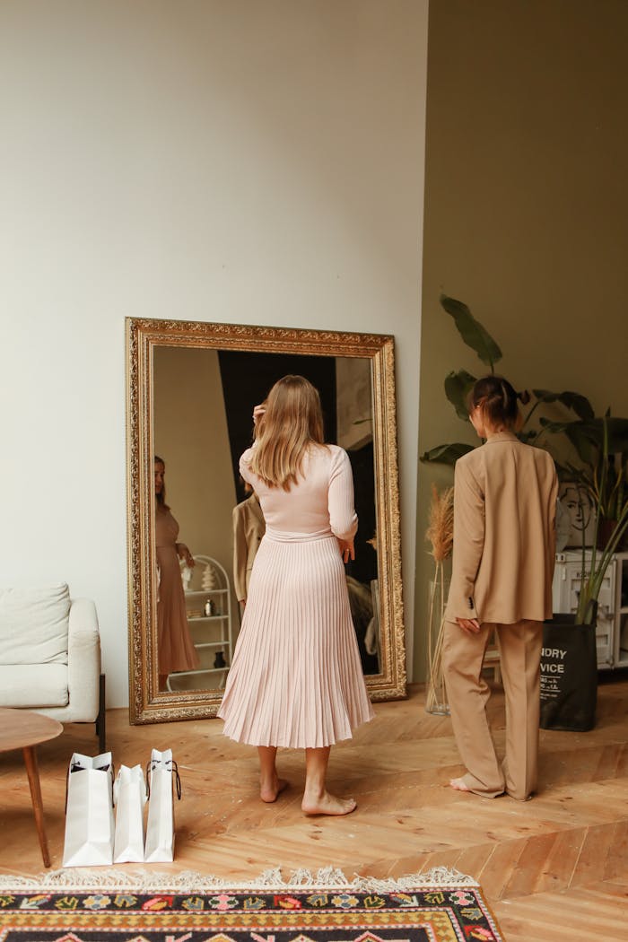 Two women trying on fashionable outfits in a boutique with large mirror.